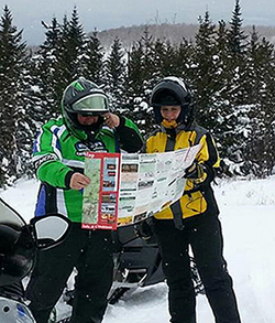 Snowmobilers with a trail map